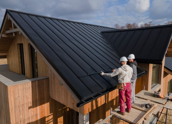 Two construction workers on a roof installing solar panels on a sunny day.