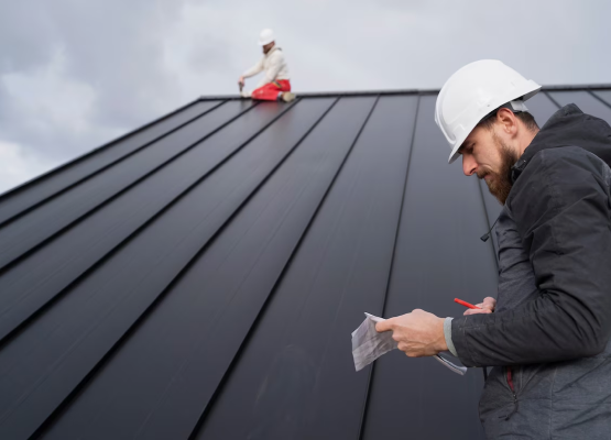 Worker on a sloped roof with another person taking notes in the foreground.