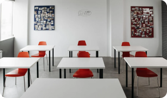 Modern classroom with white tables and red chairs, and wall art decor.