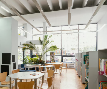 Modern library interior with bookshelves, seating area, and large windows.