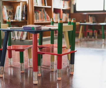 Chairs and tables with pencil-like legs in a library setting.