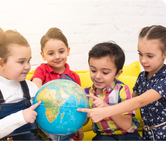 Children exploring a globe, fostering curiosity and understanding of the world around them, embodying the values for kids.