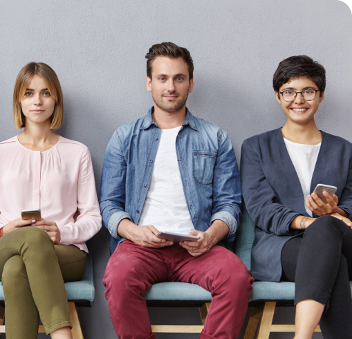 Three individuals seated on a couch, each engaged with their smartphones, representing ideal candidates in a relaxed setting.