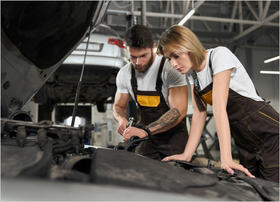 Two mechanics working together on a car in a garage, demonstrating teamwork amidst a variety of tools and equipment.