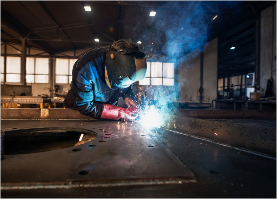 A professional welder performs steel welding in a factory, demonstrating expertise and dedication at Welding Whizzes.