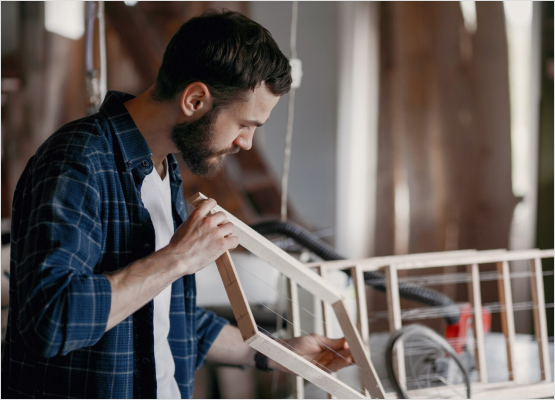 In a workshop, a skilled man assembles a wooden frame, exemplifying the expertise of Frame Experts.