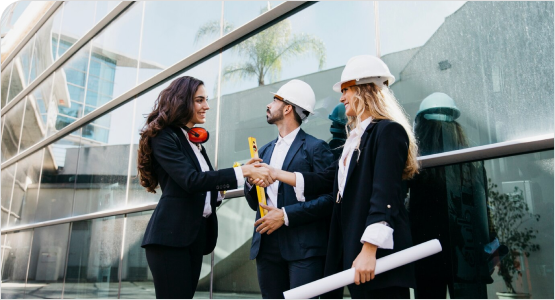 Three professionals in hard hats with blueprints outside a modern building.