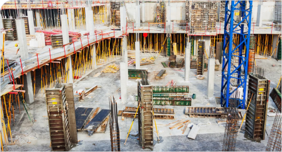 An active construction site with scaffolding, concrete forms, and a blue crane.