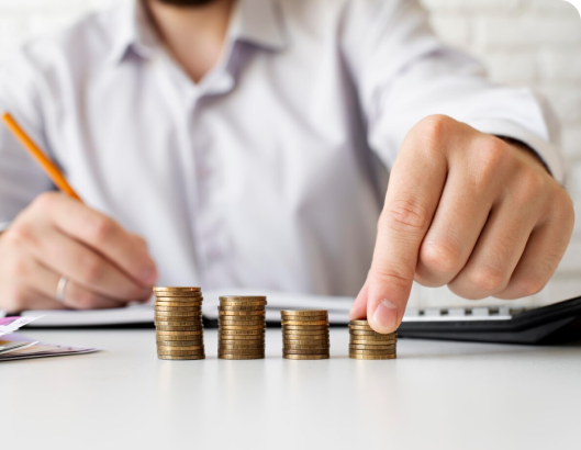 A focused man counts coins on a desk, illustrating the concept of managing finances with lower upfront costs.