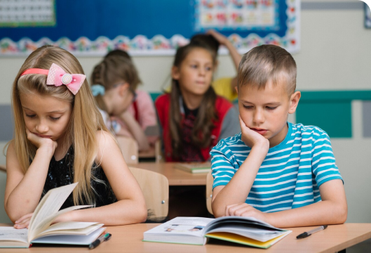 Two children at desks, each with books, reflect a solitary learning experience, emphasizing the concept of isolation.