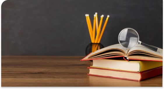 A table with books and pencils beside a blackboard, creating a cozy educational space for learning and creativity.