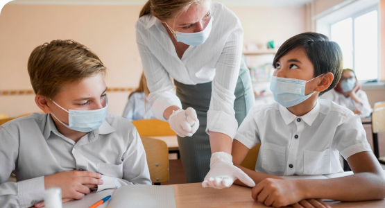 A teacher in a mask and gloves instructs students, ensuring safety with practiced emergency procedures in place.