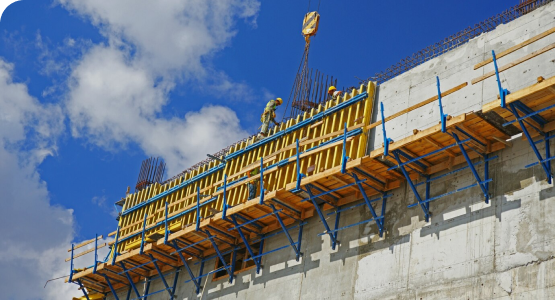 Construction workers on scaffolding reinforce a concrete wall to enhance building strength against severe weather and disasters.