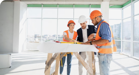 Three engineers in hard hats collaborate on a construction project, focusing on design and engineering tasks.