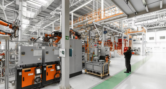 A man stands in a modular industrial warehouse surrounded by large machinery in an industrial area.