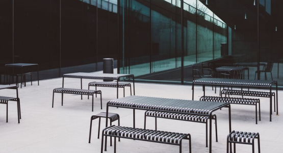 A group of tables and benches arranged in front of a large glass wall in a modular event space.