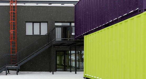 Snowy scene of a building with multiple shipping containers, designed for disaster relief modular space.