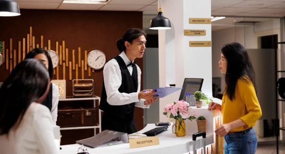 A man and woman stand at the hotel front desk, ready to check in at a modular space resort.