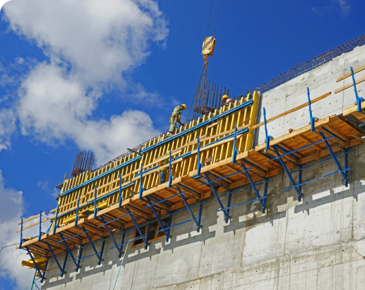 Workers on scaffolding strengthen a concrete wall, improving building resilience against extreme weather and natural disasters.