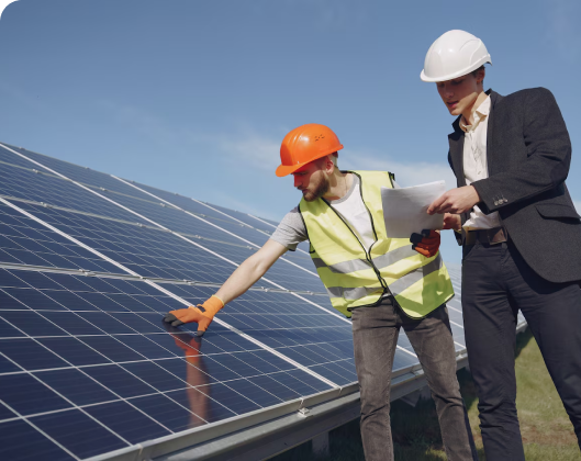 Two workers in safety gear stand next to solar panels at a modular space location.