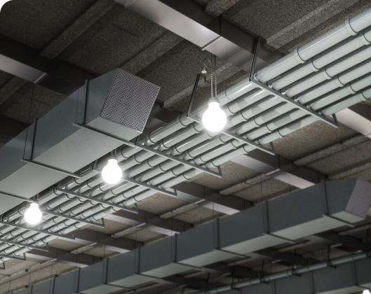 A large industrial ceiling featuring lights and pipes, highlighting indoor air quality in a modular space.