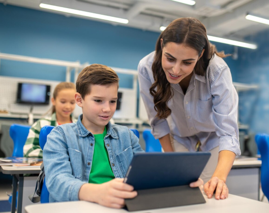 A teacher and a student are engaged in viewing content on a tablet together, sharing a moment of curiosity and learning.