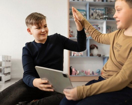 Two boys seated on the floor, engaged with a tablet, promoting accessibility and inclusivity in technology use.