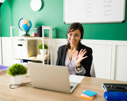 A woman in a business suit sits at a desk with a laptop, embodying teacher empowerment and professionalism in her workspace.