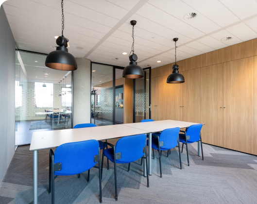 An office featuring blue chairs and a table, with movable walls and modular furniture for flexible workspace design.