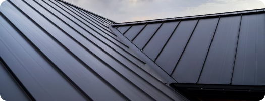 Close-up of modern metal roof sections against a cloudy sky.