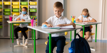 A classroom scene featuring children at desks, all wearing masks, highlighting a safe learning environment.