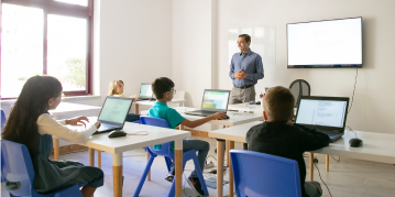 A group of children engaged at desks, each using a laptop for learning and collaboration in a classroom setting.